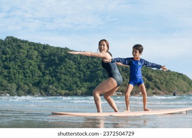 Mother teaches son the basics of surfing, surfing lessons on the beach, lifestyle activities, water sports - Powered by Shutterstock