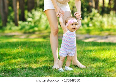 Mother Teaching Baby To Walk In The Park