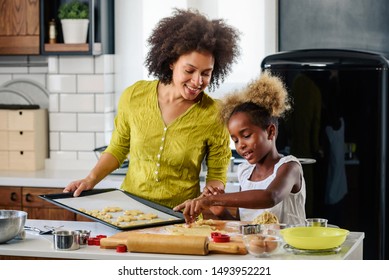 Mother Teaching Child To Cook And Help In The Kitchen. African American Mother And Daughter Making Cookies At Home. 