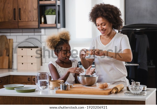 Mother\
Teaching Child to Cook and Help in the Kitchen. African American\
Mother and Daughter making cookies at home.\
