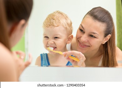 Mother Teaching Child Teeth Brushing. Mom Cleaning Son's Teeth And Looking At Mirror Reflection