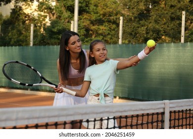 Mother teaching daughter to play tennis on court - Powered by Shutterstock