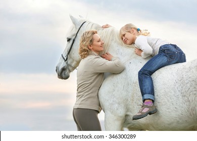 Mother teaching daughter to ride a horse. - Powered by Shutterstock