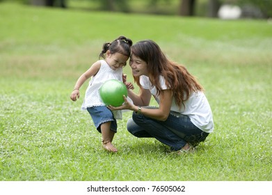 Mother Teaching Daughter To Soccer Ball In The Park Happily. Teen Mothers, Care , Love And Warmth Closely. Teaching Learning Outside The Classroom On Mother's Day 