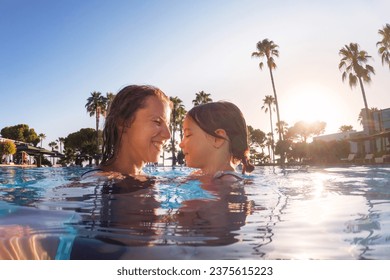 Mother teaching daughter to swim in pool during summer vacation. Mother and daughter playing in water. Beach resort vacation by the sea. Winter or summer seaside holiday. - Powered by Shutterstock