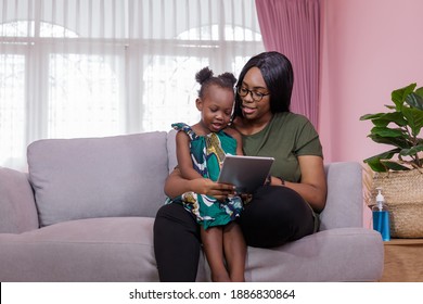 Mother was teaching the daughter through tablet joyfully while sitting on the sofa. black people or African Americans. Home study concept. Parent-teacher concept. - Powered by Shutterstock