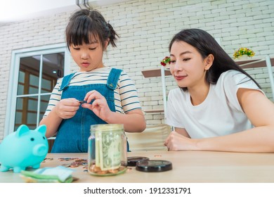 Mutter unterrichtet Tochter über das Sparen und Planen von Geld, indem sie Spardose und Sparschwein mit echtem Geld für das Geld- und Vermögensbildungskonzept nutzt.