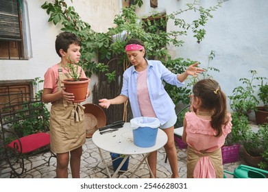 Mother teaching her children how to plant flowers in the garden. The family enjoys a sunny day outside, focusing on gardening and teamwork. Children actively participate wearing aprons. - Powered by Shutterstock