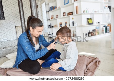 Mother teasing her son with index finger while playing at home in the living room