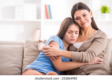 Mother And Teen Daughter Are Hugging After Quarrel On Sofa At Home.