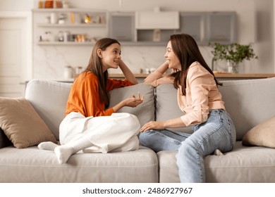 Mother and teenage daughter chatting, girl sharing secrets with loving mum, having pleasant conversation, sitting on sofa. Good trusted family relationship - Powered by Shutterstock