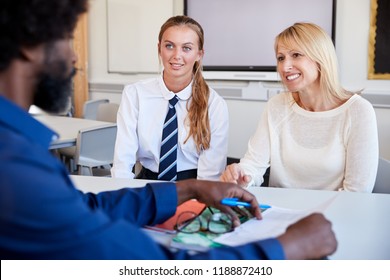 Mother And Teenage Daughter Having Discussion With Male Teacher At High School Parents Evening