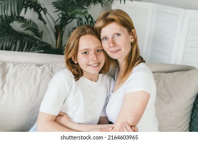 Mother And Teenage Daughter Hugging At Home On The Couch. A Generation Of Women In The Same Family. Spend Time With Family. Mom Gently Hugged Her Red-haired Daughter To Her. Genetics Concept