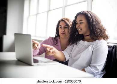 A Mother And Teenage Daughter Looking At Laptop Together