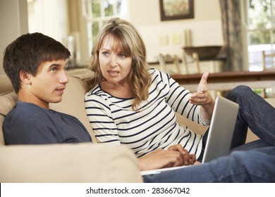 Mother And Teenage Son Arguing On Sofa At Home