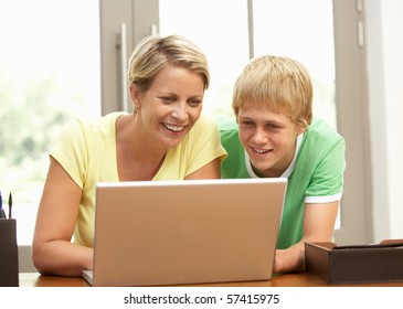 Mother And Teenage Son Using Laptop At Home