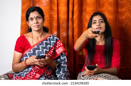 Mother And Teenager Daughter Busy Using Mobile Phone While Watching Tv At Home - Concept Of Modern Day Lifestyle By Performing Multiple Activities, Family And Togetherness