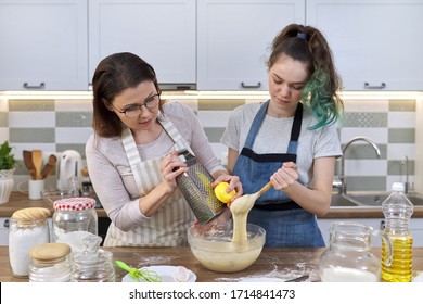 Mother And Teenager Daughter Cook Together At Home In Kitchen. Girl Helps Her Mom Stir Dough, Woman Rubs Lemon Zest. Parent Teen Communication, Family, Mothers Day