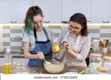 Mother And Teenager Daughter Cook Together At Home In Kitchen. Girl Helps Her Mom Stir Dough, Woman Rubs Lemon Zest. Parent Teen Communication, Family, Mothers Day