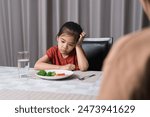 Mother is telling her cute kid eat useful vegetables but the child refuses to eat.