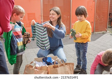 Mother of three children, Ukrainian refugee, looking gratefully at clothes and toys European volunteer gave them to support. Humanitarian aid and helping hand from world for Ukraine during the war - Shutterstock ID 2137631491