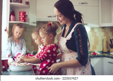 Mother With Three Kids Cooking Holiday Pie In The Kitchen, Casual Lifestyle Photo Series In Real Life Interior