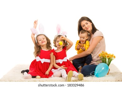 Mother And Three Kids Prepare For Easter Holiday  And Sitting Together On Carpet