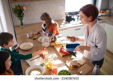 Mother of three little children preparing breakfast in kitchen at home. - Powered by Shutterstock