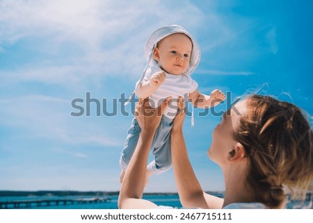 Mother throwing baby up against the blue sky. Happy family outdoors. Mom and baby at summer on nature. Positive human emotions and feelings.