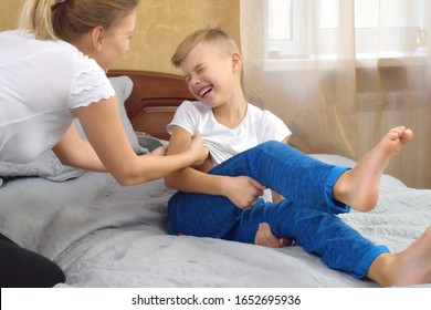 Mother tickles the child. Tickling and laughter. Mother and son together having fun. Mother touch baby son. Games with children at home