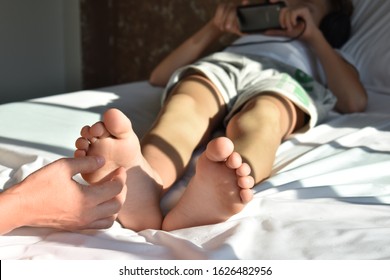 Mother tickling son. mobile addiction in children. Tickle the heels of the child.