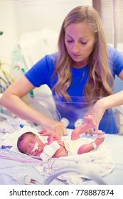 Mother Touching Her Premature Newborn Baby As He Is Hooked Up To An IV And Health Monitors While Being Treated In Intensive Care At The Hosptial