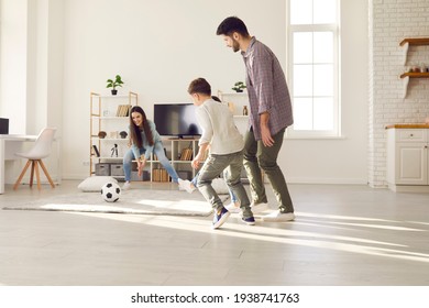 Mother Trying To Catch Soccer Ball Having Fun With Adorable Family At Home. Sport Activity And Leisure Fun During Quarantine Due To Coronavirus Pandemic. Happy Caucasian Parents And Children Together