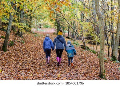 Mother And Two Children Walking Away From The Camera On A Muddy Trail.