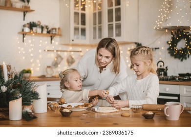 mother and two daughters prepare homemade Christmas gingerbread in the kitchen decorated for the New Year. Traditional holiday cooking with the whole family. Toned defocused noise vintage image - Powered by Shutterstock