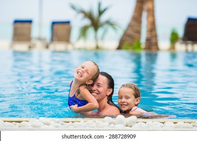 Mother And Two Kids Enjoying Summer Vacation In Luxury Swimming Pool