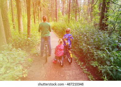 mother with two kids riding bikes in forest