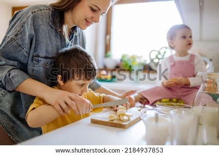 Mother of two little children preparing breakfast in kitchen at home.