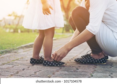 Mother tying shoe  little girl in the park selective focus. - Powered by Shutterstock