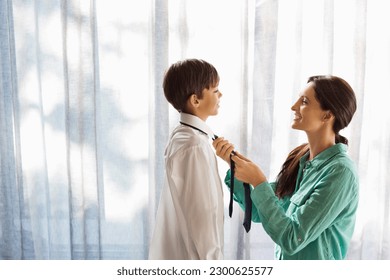 Mother tying son's tie at window - Powered by Shutterstock