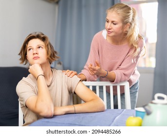 Mother And Unhappy Teenage Son Sitting After Quarrel At Home, Mother Consoles Son