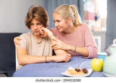 Mother And Unhappy Teenage Son Sitting After Quarrel At Home, Mother Consoles Son