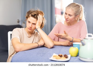 Mother And Unhappy Teenage Son Sitting After Quarrel At Home, Mother Consoles Son