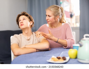 Mother And Unhappy Teenage Son Sitting After Quarrel At Home, Mother Consoles Son