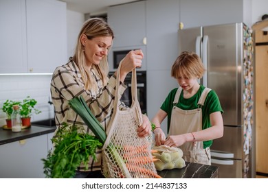 Mother unpacking local food in zero waste packaging from bag with help of daughter in kitchen at home. - Powered by Shutterstock