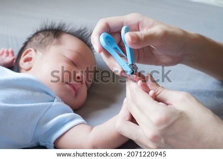 Mother use Nail Trimmer with baby hand on bed Foto d'archivio © 