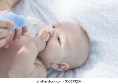 Mother Using Baby Nasal Aspirator. She Is Doing A Mucus Suction To Three Months Baby Boy