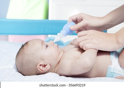 Mother Using Baby Nasal Aspirator. She Is Doing A Mucus Suction To Three Months Baby Boy