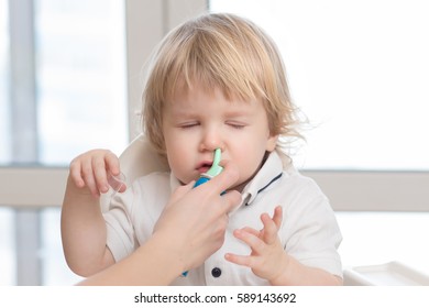 Mother Using Baby Nasal Spray For The Common Cold, Saline Sea Water Helps Heal The Snot For Child Or Kid.