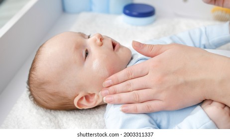 Mother Using Creme And Lotion To Prevent Her Baby Skin From Drying. Concept Of Hygiene, Baby Care And Healthcare.